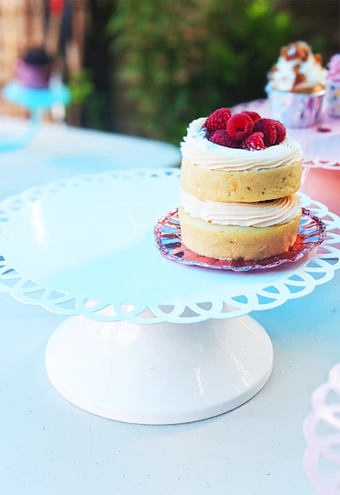 Delicious cakes decorated with fresh fruits and cream on a white cake stand