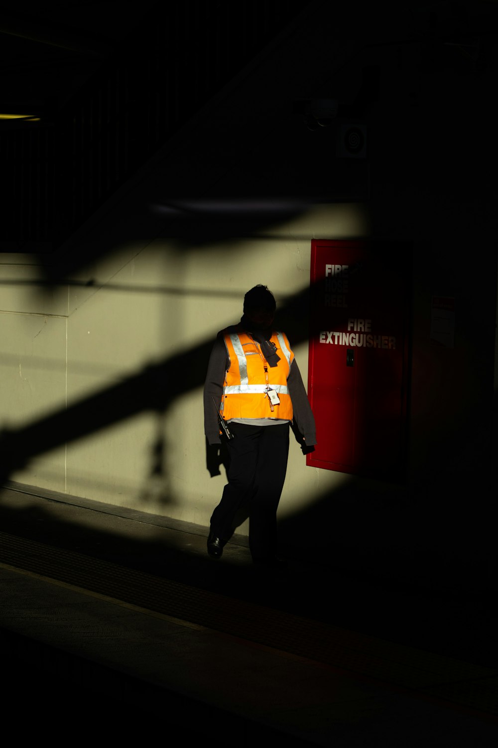 man in yellow shirt and black pants standing in front of red door