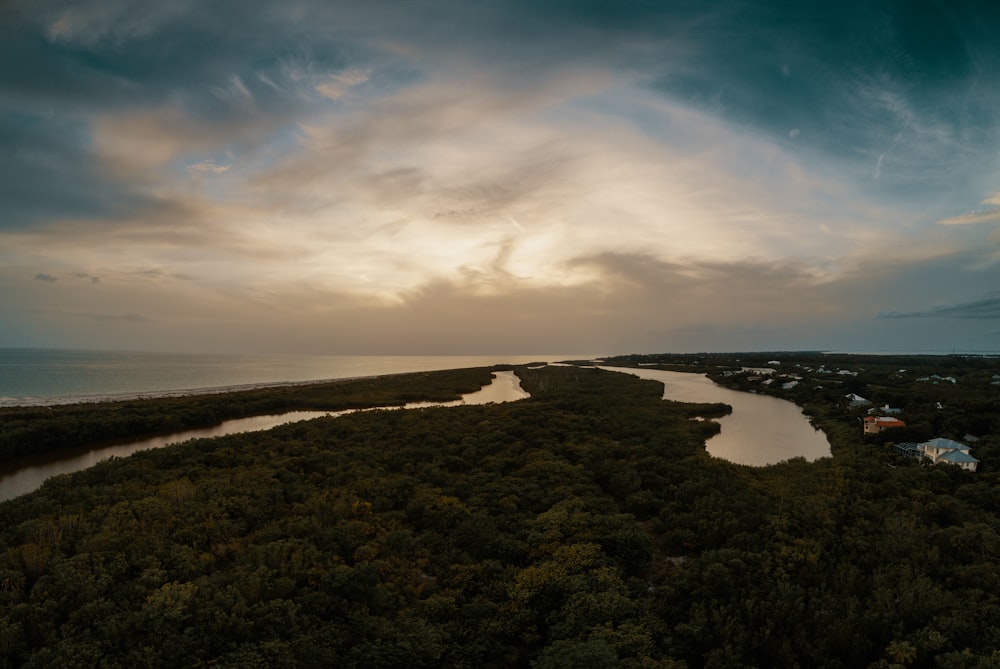 campo de grama verde perto do corpo de água sob o céu azul durante o dia