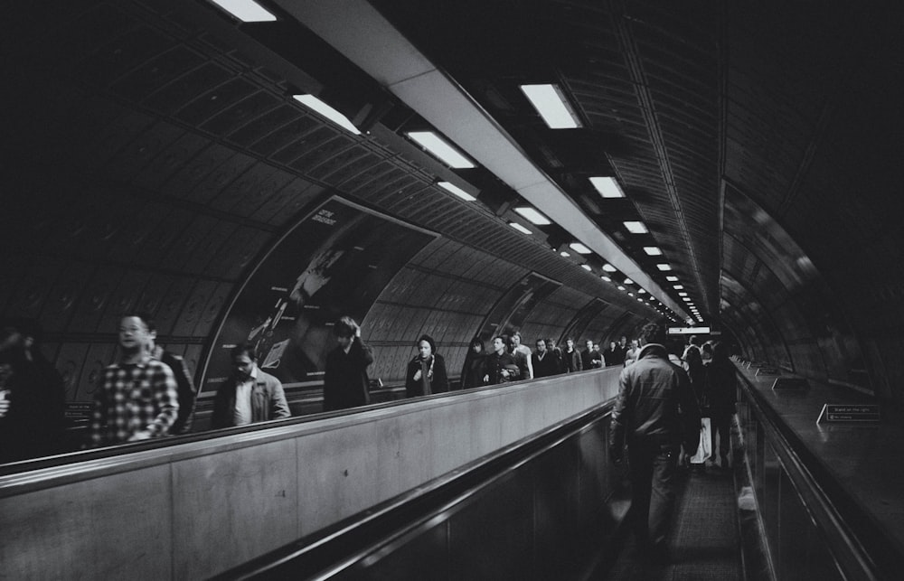 people walking on the train station in grayscale photography