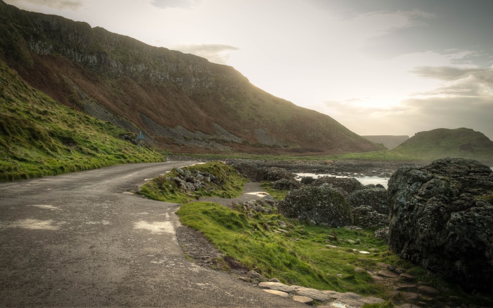 gray road between green and brown mountains during daytime