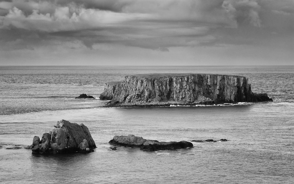 grayscale photo of rock formation on sea