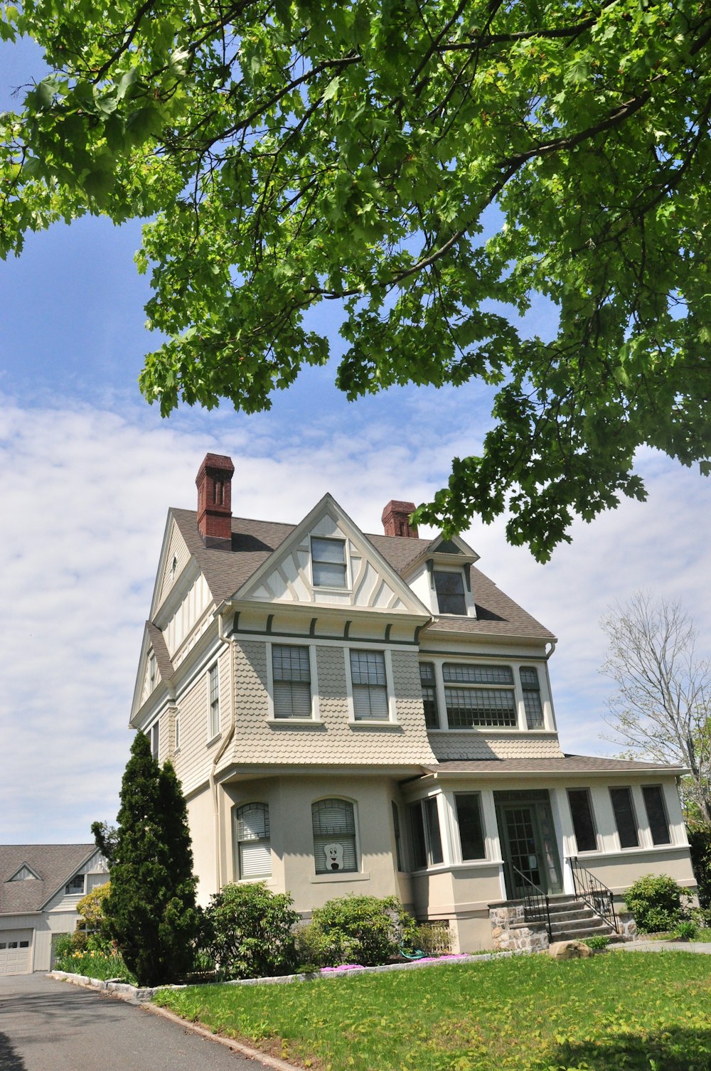 white and brown concrete house near green tree under blue sky during daytime