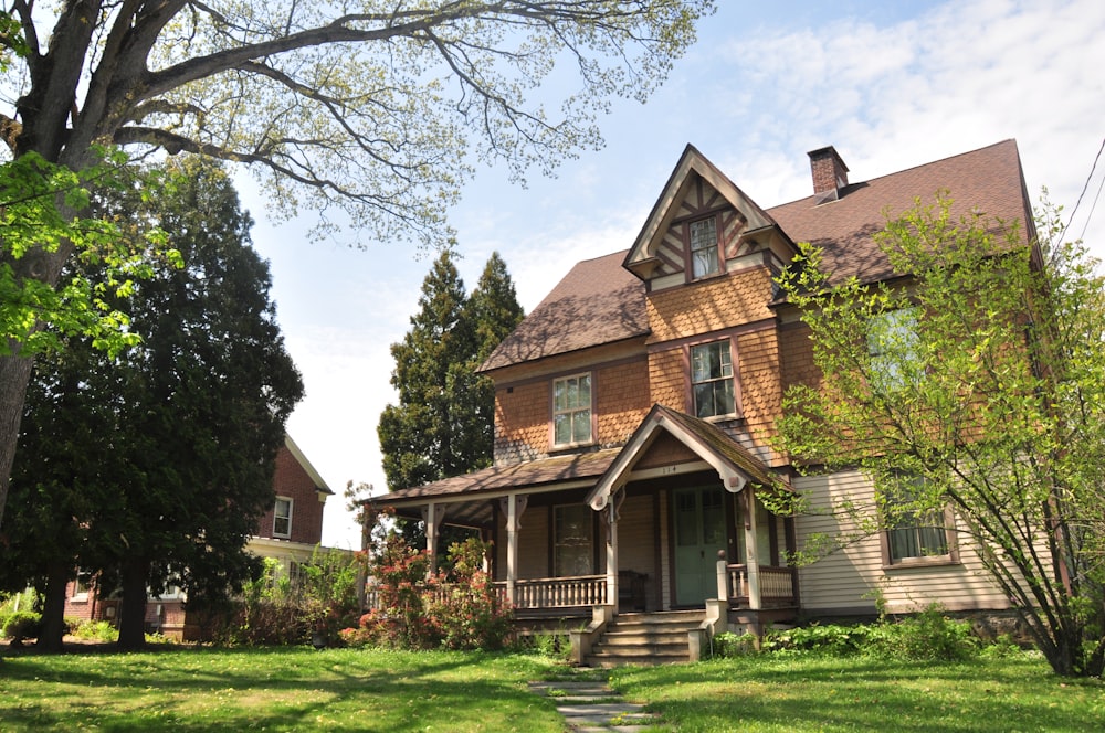 brown brick house near green grass field and trees during daytime