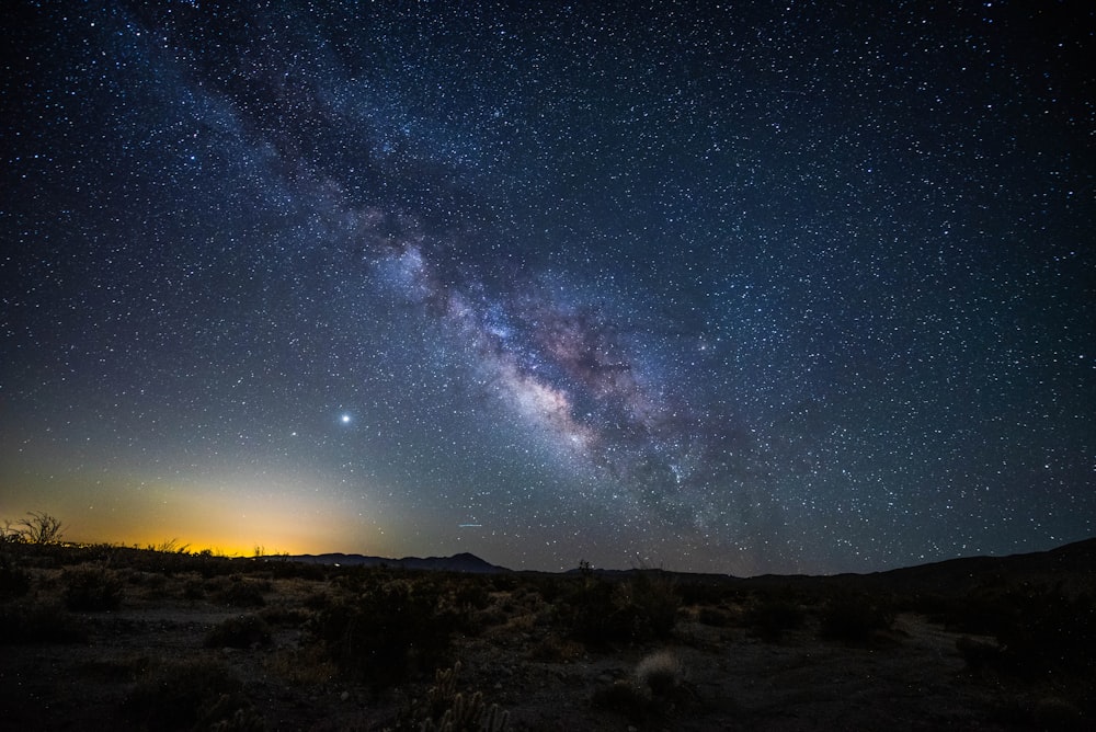 silhouette of mountain under blue sky with stars during night time