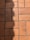 A section of red-orange floor tiles, each tile rectangular in shape, arranged in a regular pattern with visible grout lines in between. The tiles exhibit some signs of wear and darker patches, suggesting age or frequent use. A shadow is cast across part of the tiles, adding contrast to the composition.