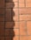 A section of red-orange floor tiles, each tile rectangular in shape, arranged in a regular pattern with visible grout lines in between. The tiles exhibit some signs of wear and darker patches, suggesting age or frequent use. A shadow is cast across part of the tiles, adding contrast to the composition.
