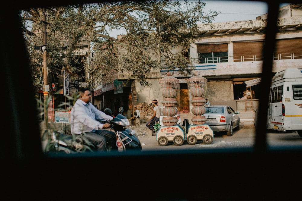 man in white dress shirt and black pants sitting on black motorcycle near brown tree during