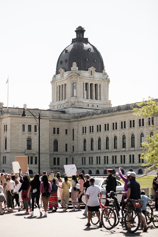 people standing near brown concrete building during daytime in Saskatchewan Legislative Building Canada