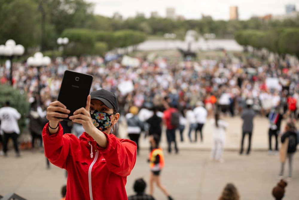 woman in red long sleeve shirt holding black smartphone