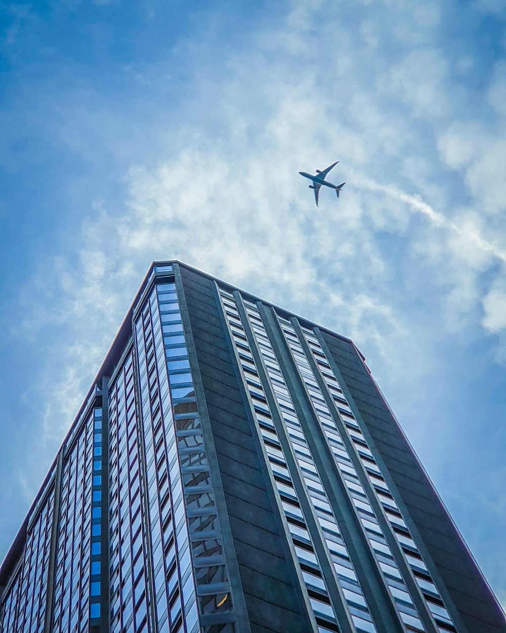 white airplane flying over gray concrete building during daytime