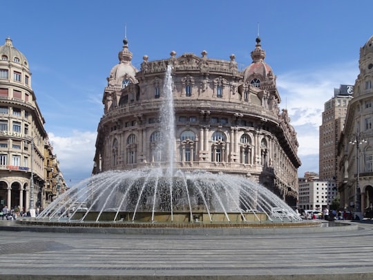 white concrete building with water fountain during daytime in Piazza De Ferrari Italy