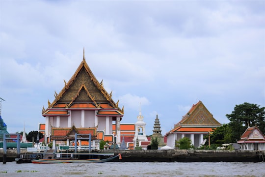 brown and white concrete building near body of water during daytime in Chao Phraya River Thailand