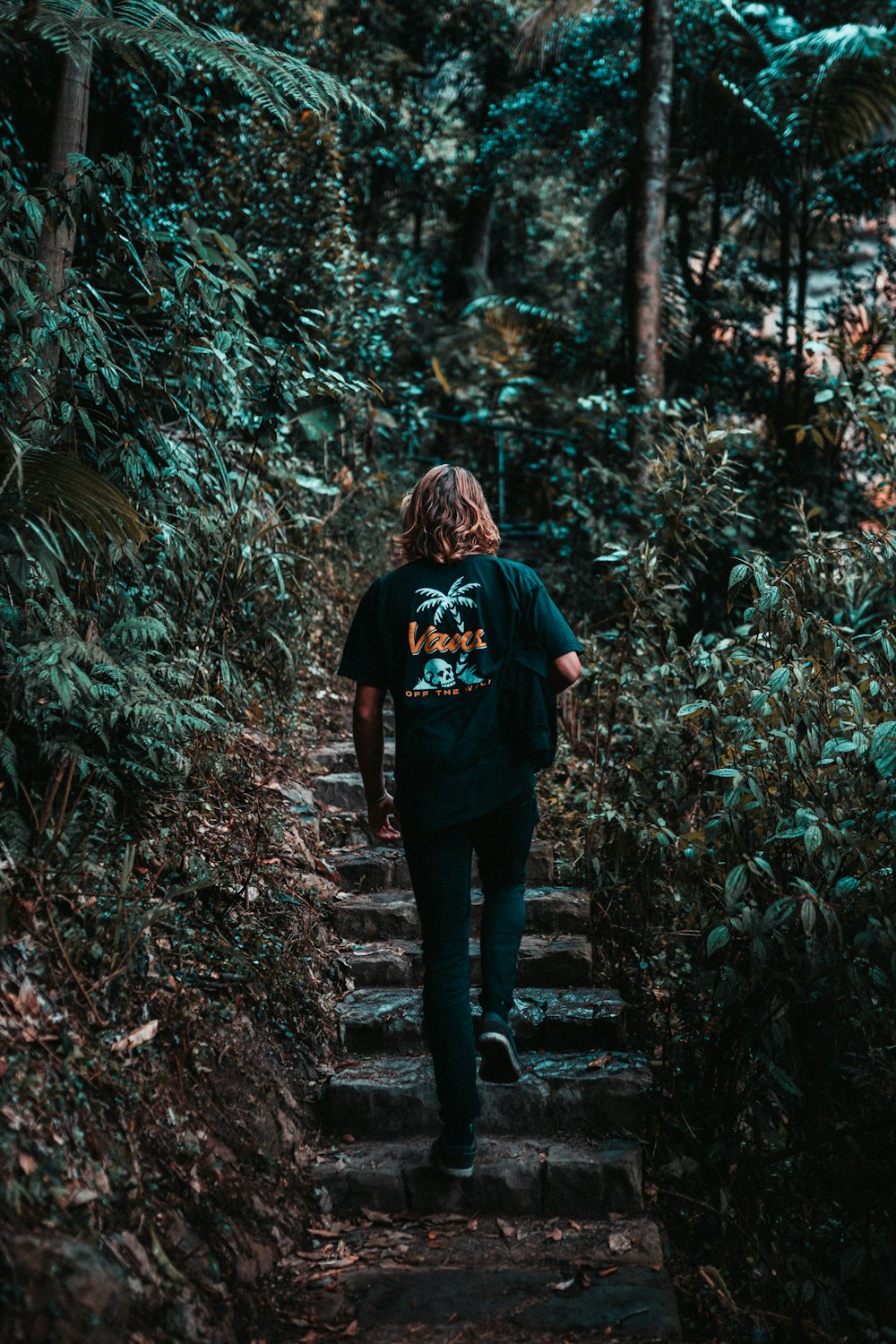mulher na jaqueta preta em pé na floresta durante o dia
