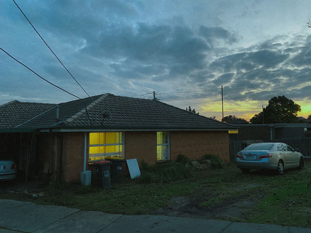 white car parked beside yellow and brown house