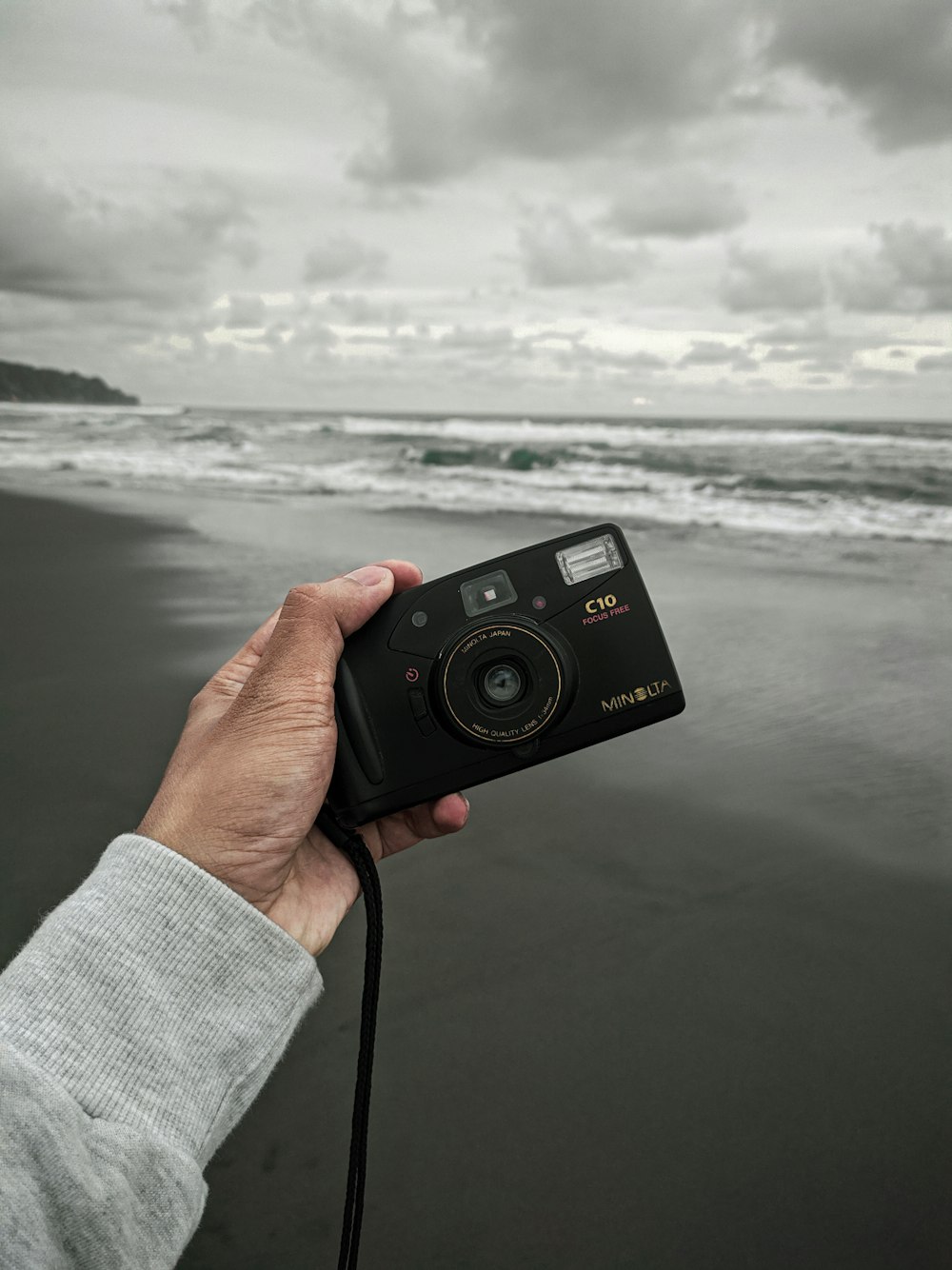 person holding black point and shoot camera