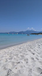 A serene private beach with turquoise waters and a luxury yacht anchored offshore.
