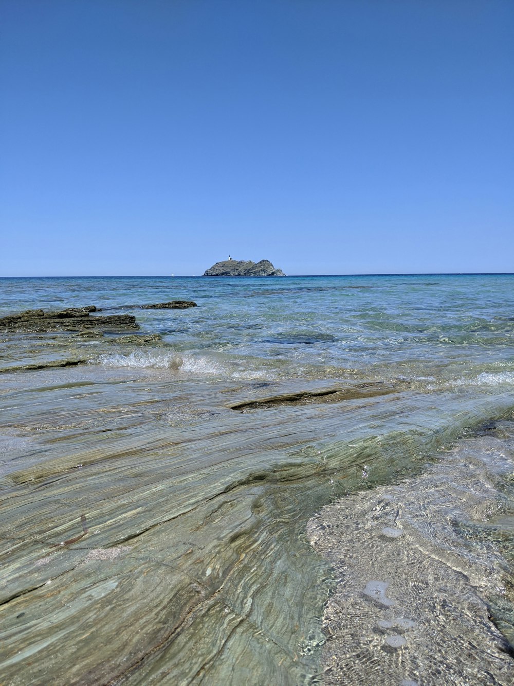 brown rock formation on sea under blue sky during daytime