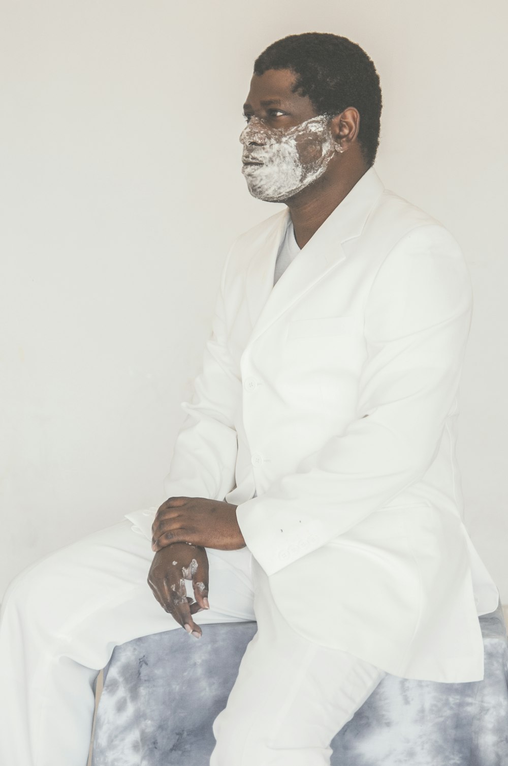 man in white dress shirt and white pants sitting on white chair