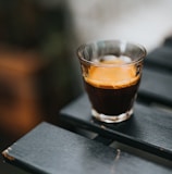 clear drinking glass with brown liquid on black table