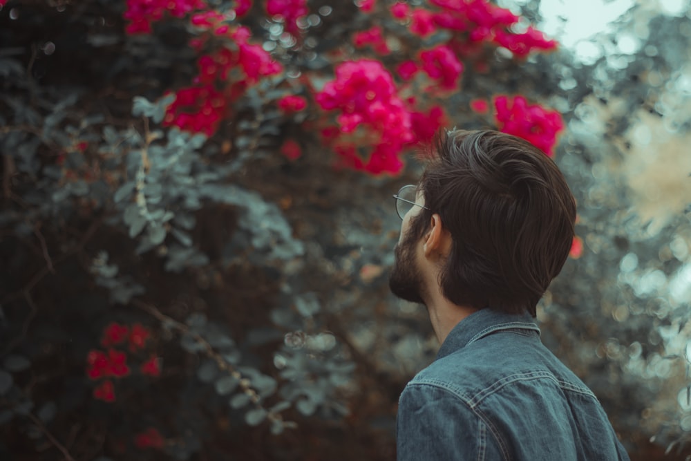 woman in blue denim jacket standing near pink flowers during daytime