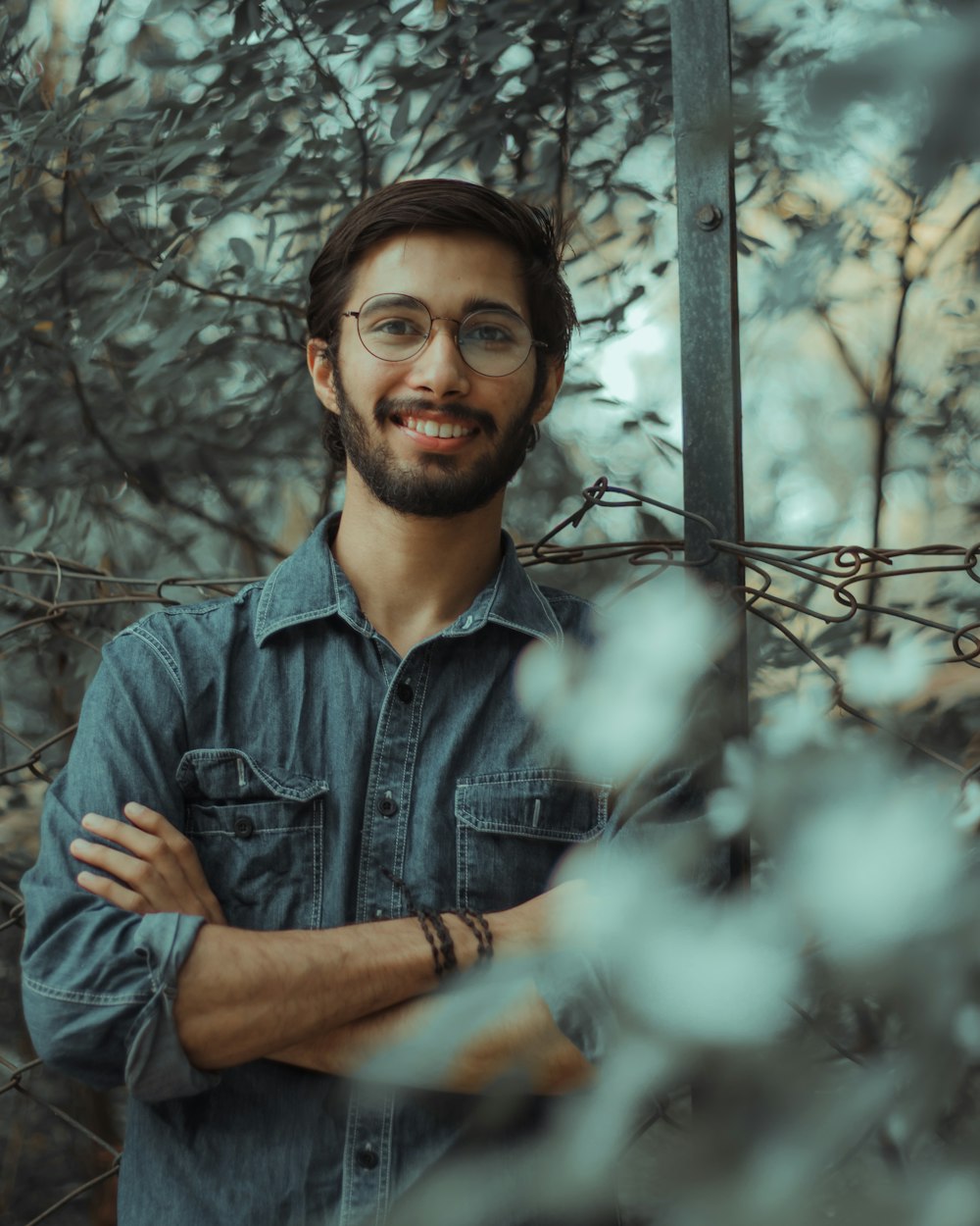 man in blue denim button up shirt standing near tree