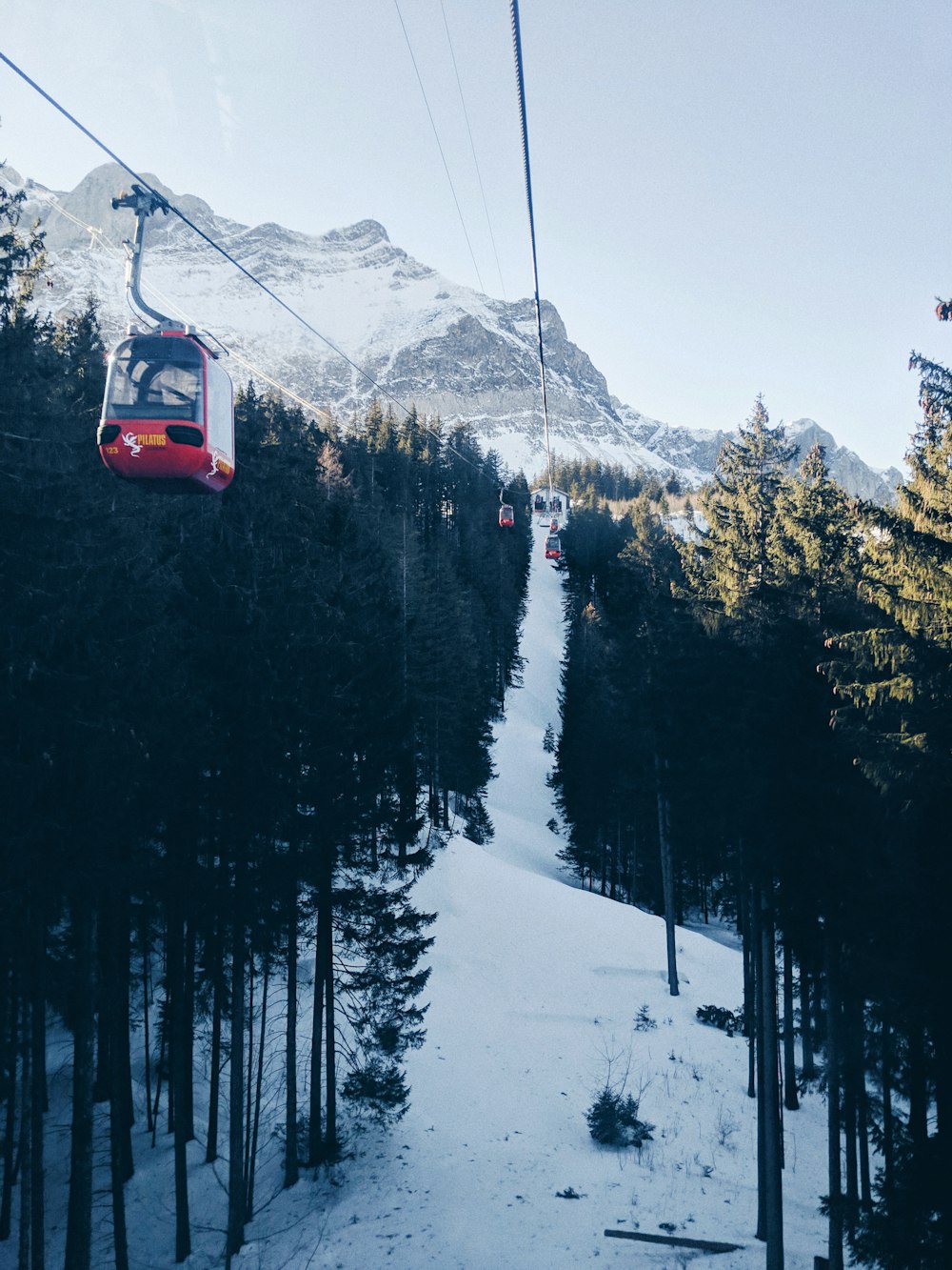red cable car over snow covered mountain during daytime