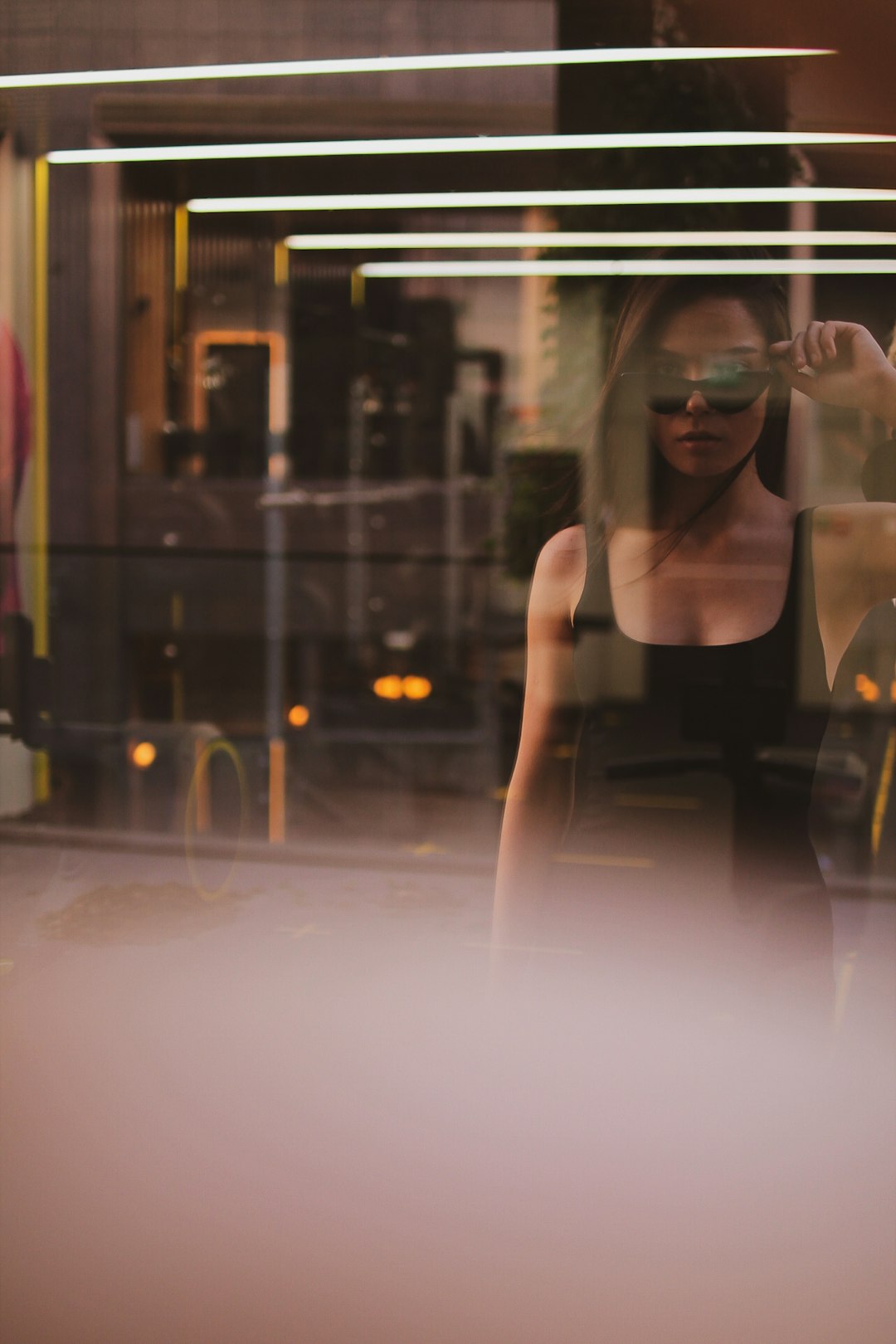 woman in black tank top standing near glass window