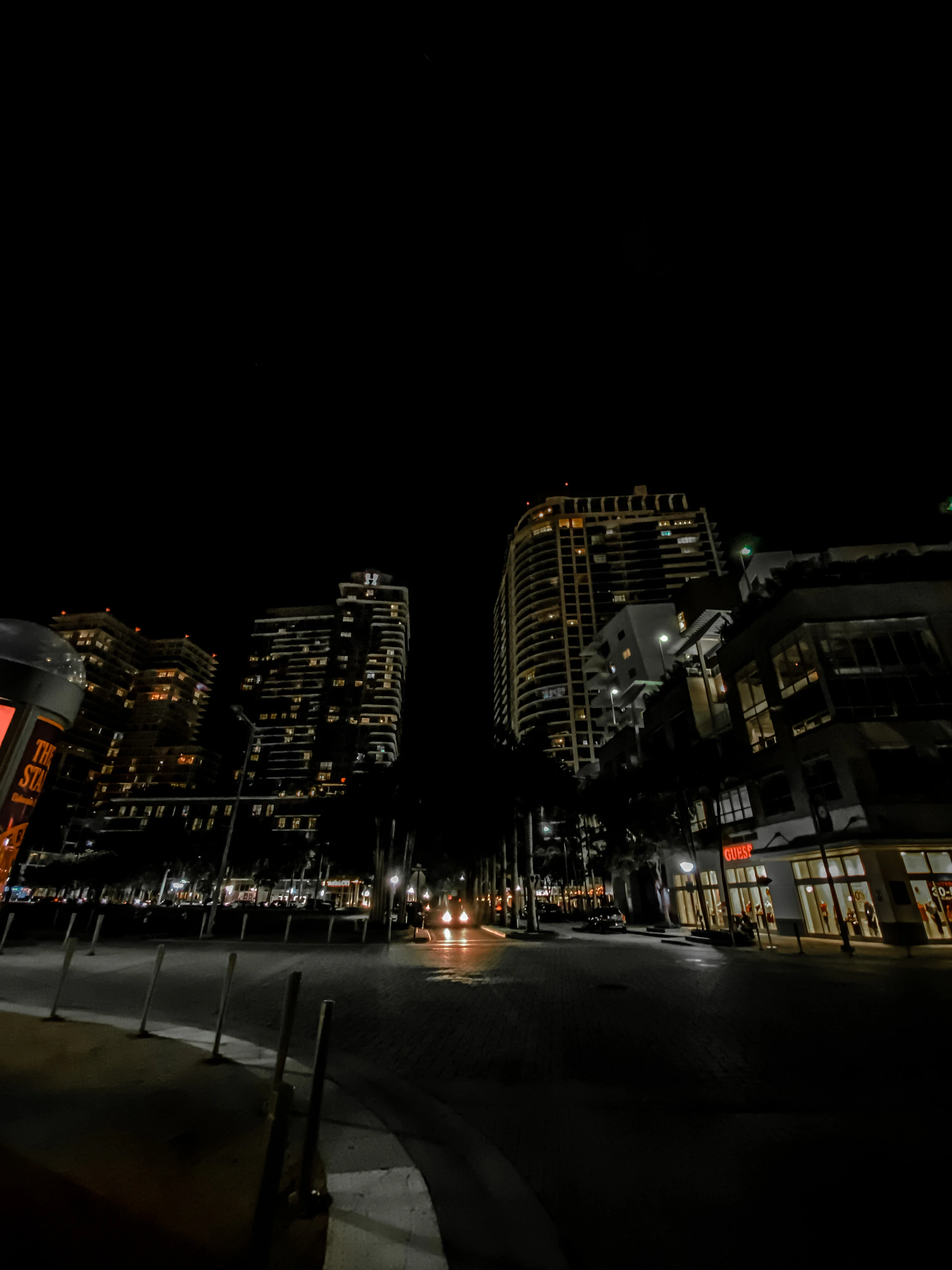 A cinematic still capturing a softly lit urban nightscape with deep blue and black tones, evoking a serene and immersive atmosphere.