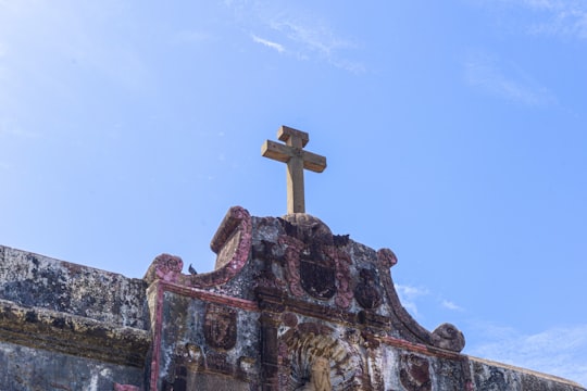 brown and green concrete cross under blue sky during daytime in Nani Daman Fort India