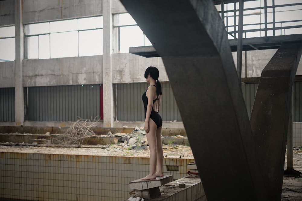 woman in black bikini bottom and black stockings standing on brown wooden dock during daytime