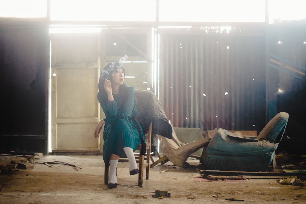 Donna in camicia blu a maniche lunghe seduta sulla poltrona di legno marrone
