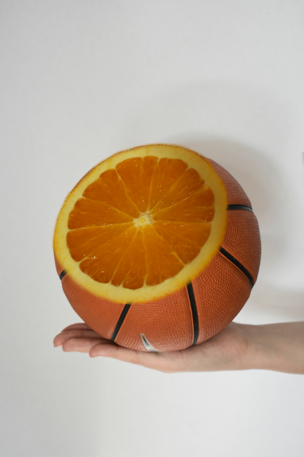 personne tenant un fruit orange sur une surface blanche