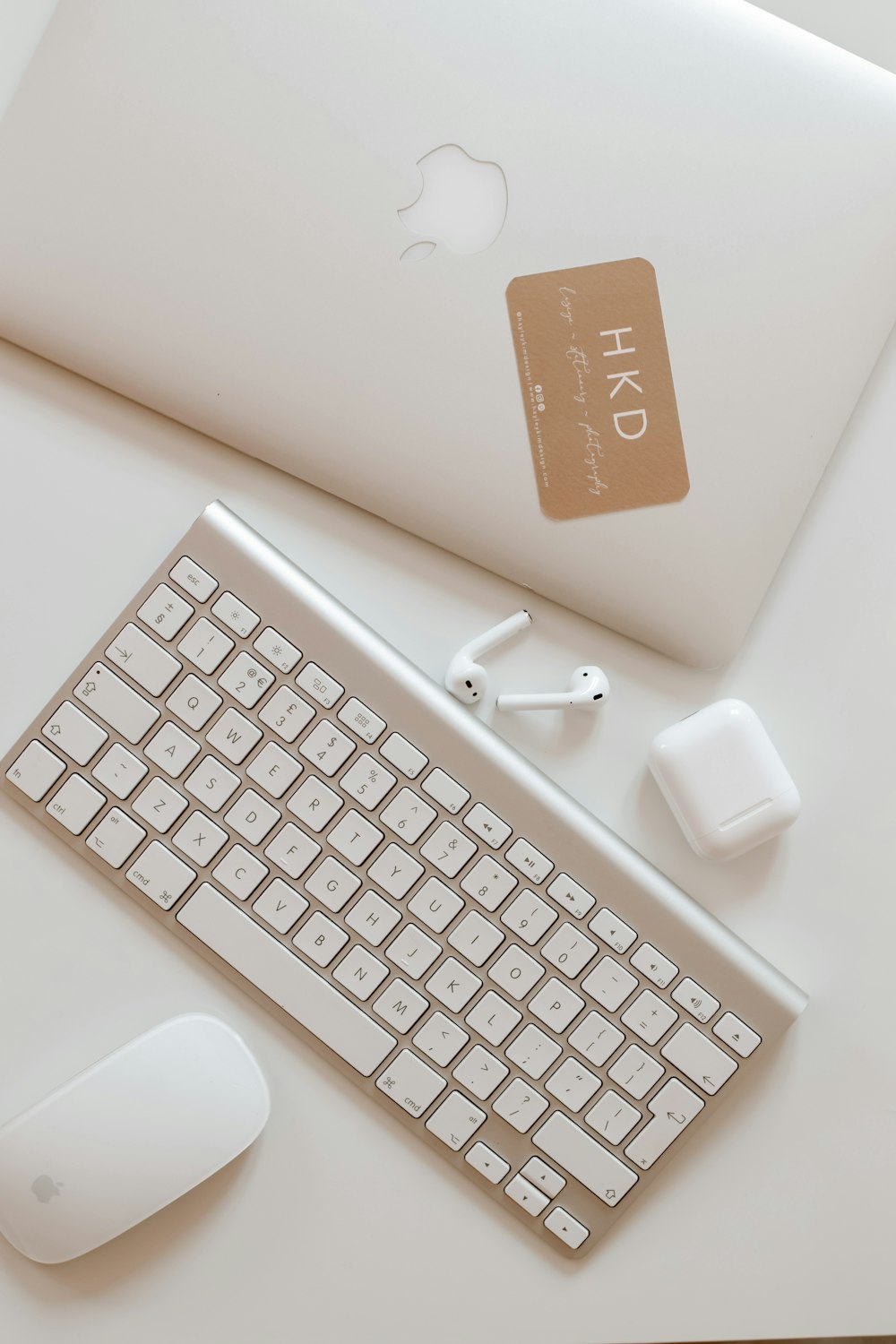 white apple keyboard with white earbuds