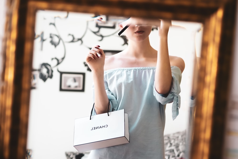 Mujer con camisa blanca sosteniendo papel blanco de impresora