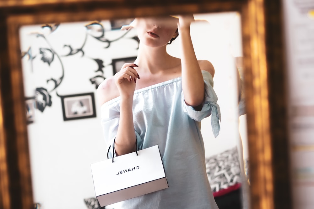 woman in white long sleeve shirt holding white printer paper