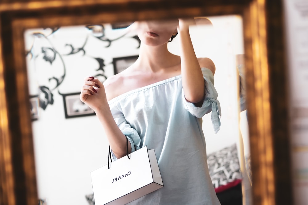 woman in white tank top holding white printer paper