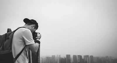 grayscale photo of man taking photos of the landscape in front of him