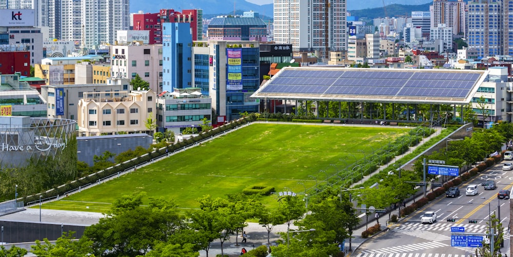 aerial view of green grass field near city buildings during daytime