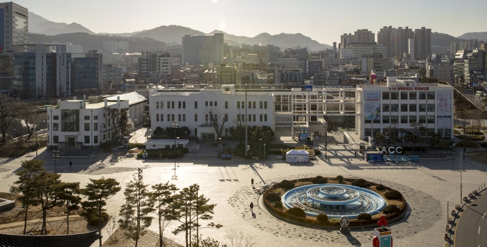 white and blue round fountain in the middle of city buildings during daytime