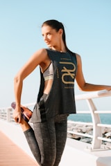 woman in black tank top and gray pants standing on white metal railings during daytime