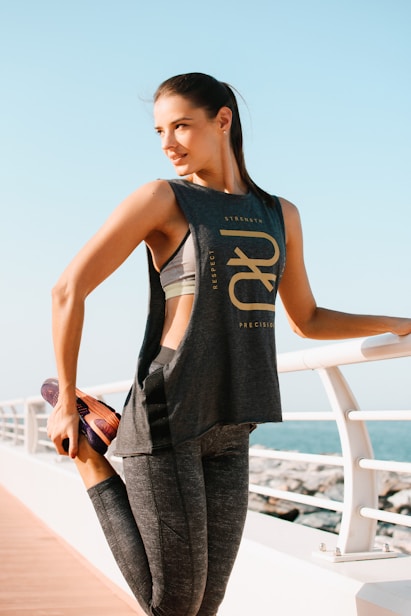 woman in black tank top and gray pants standing on white metal railings during daytime