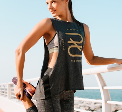 woman in black tank top and gray pants standing on white metal railings during daytime