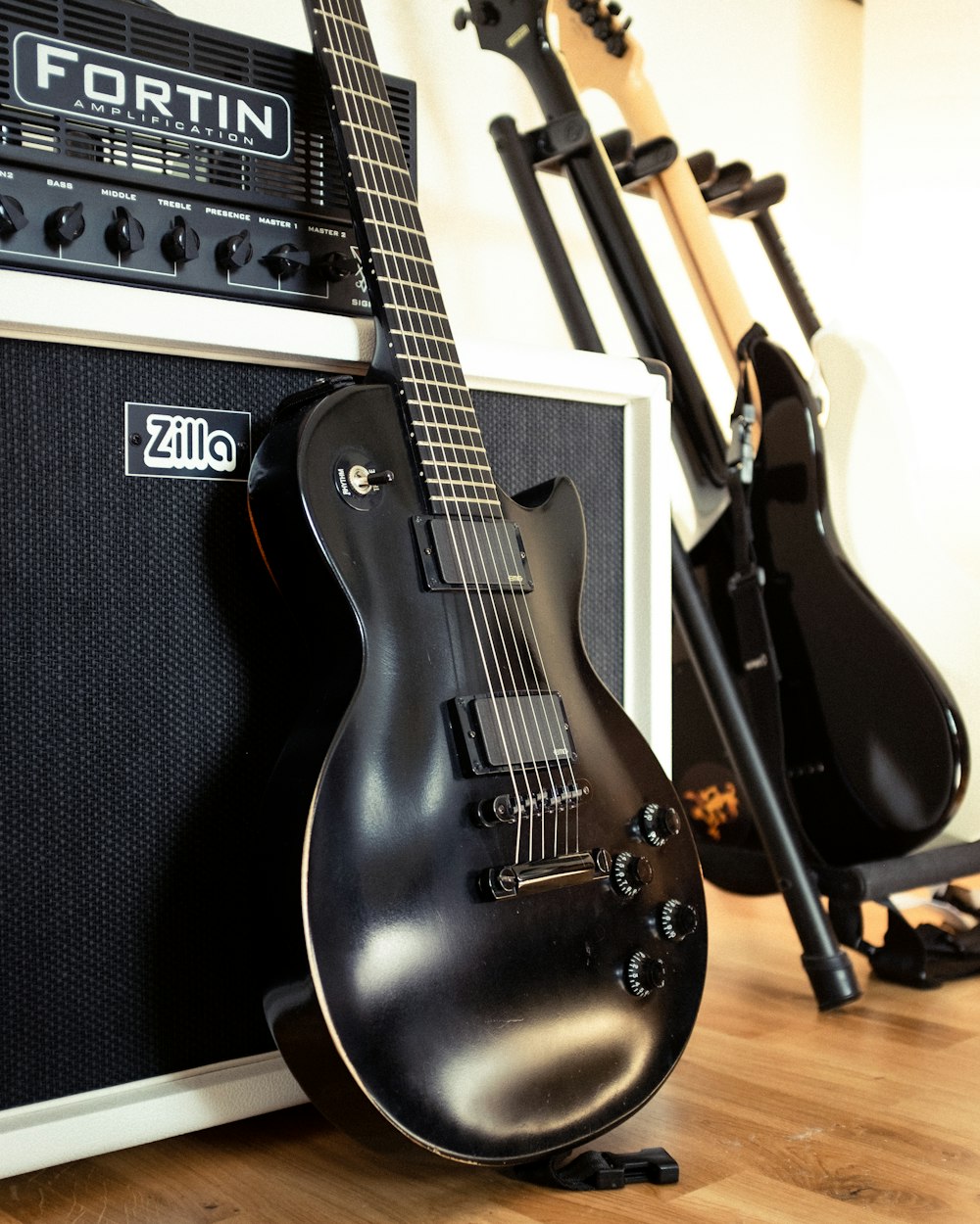 black electric guitar beside black guitar amplifier