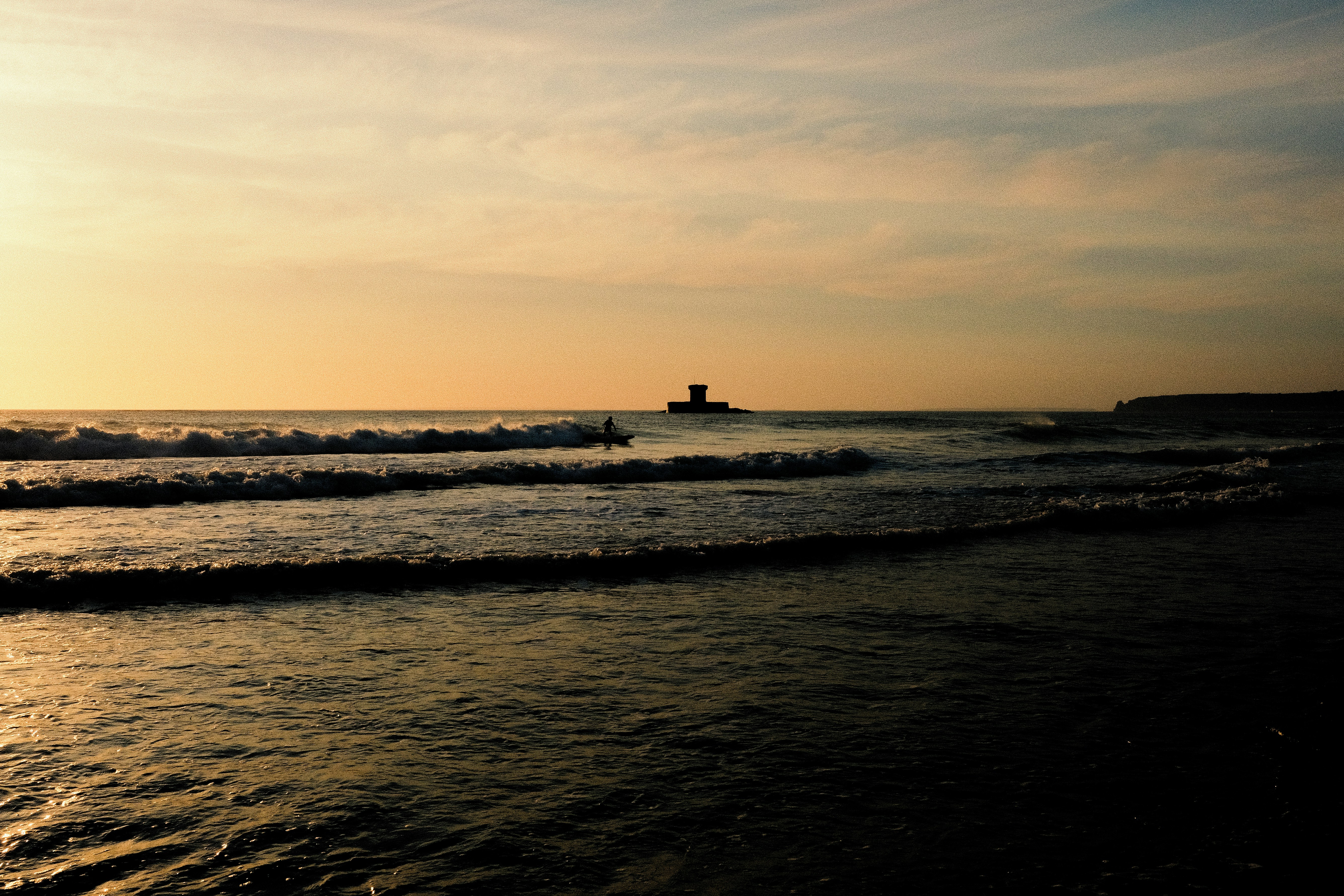 silhouette of lighthouse on sea during sunset