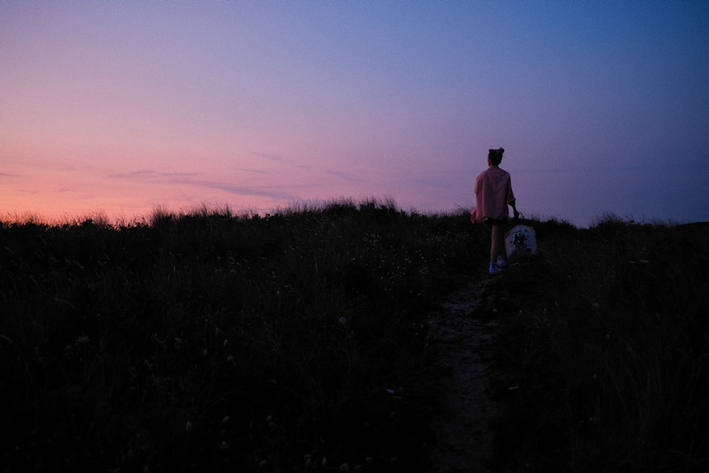 man in white shirt standing on green grass during sunset