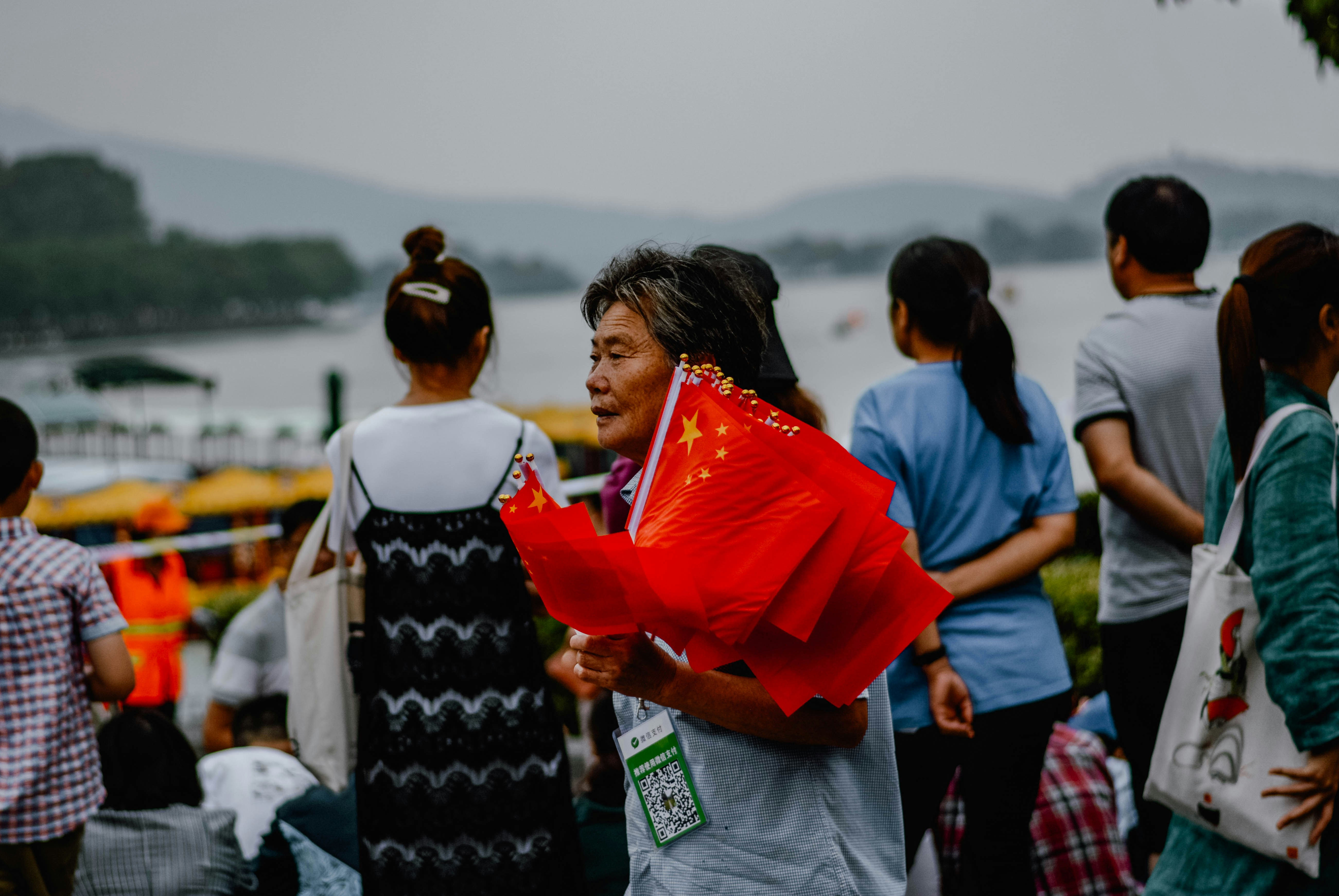 person in blue shirt holding chinese flags