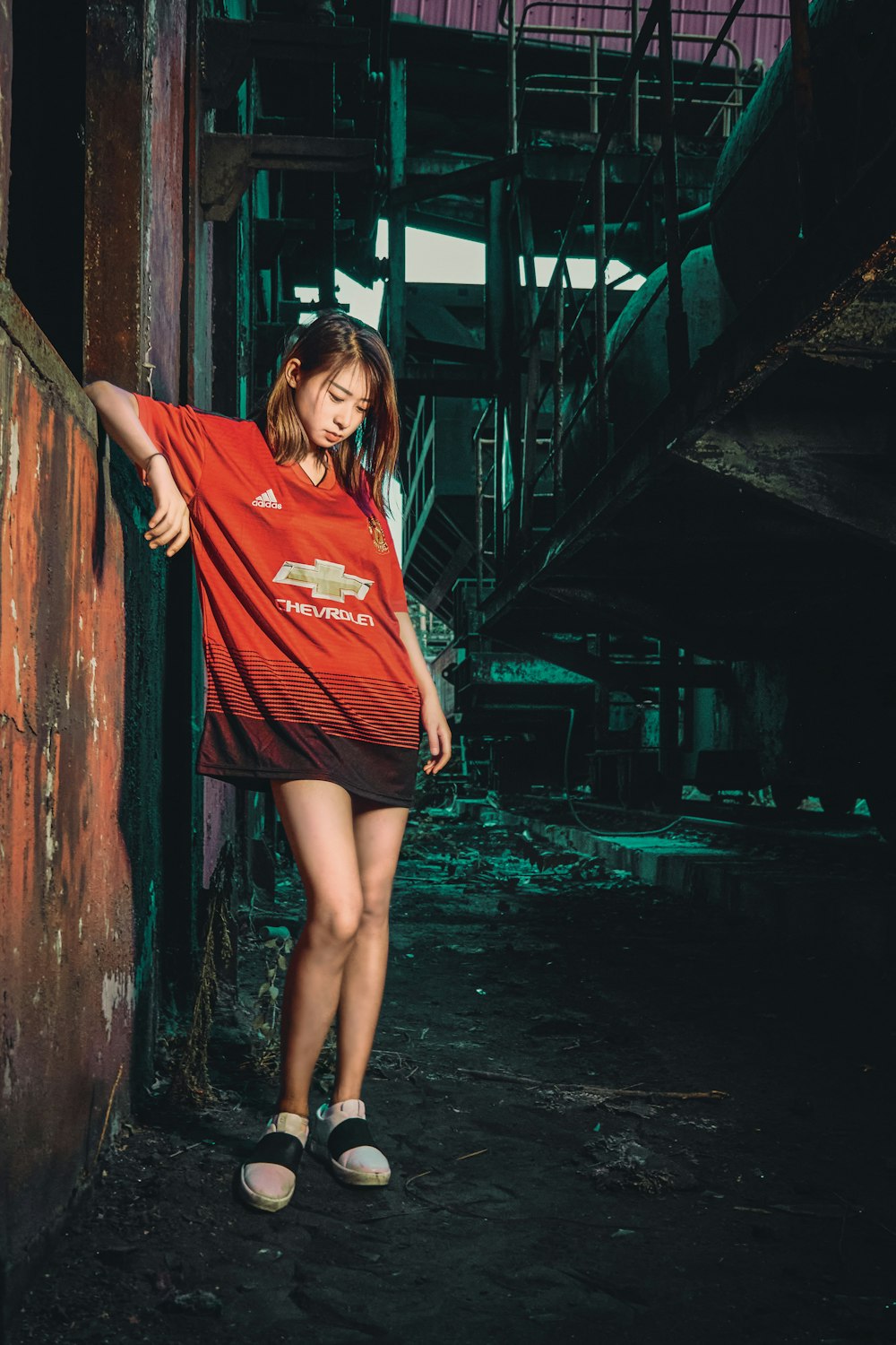 woman in red crew neck t-shirt standing beside brown wooden post