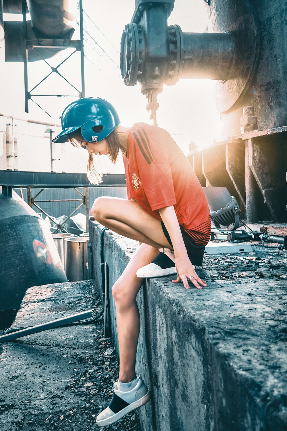 woman in orange t-shirt and blue helmet sitting on rock