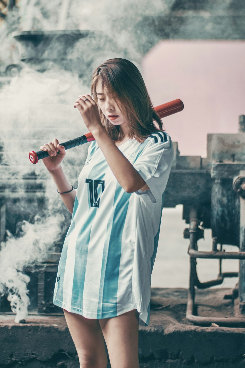 woman in white and blue long sleeve shirt holding red baseball bat